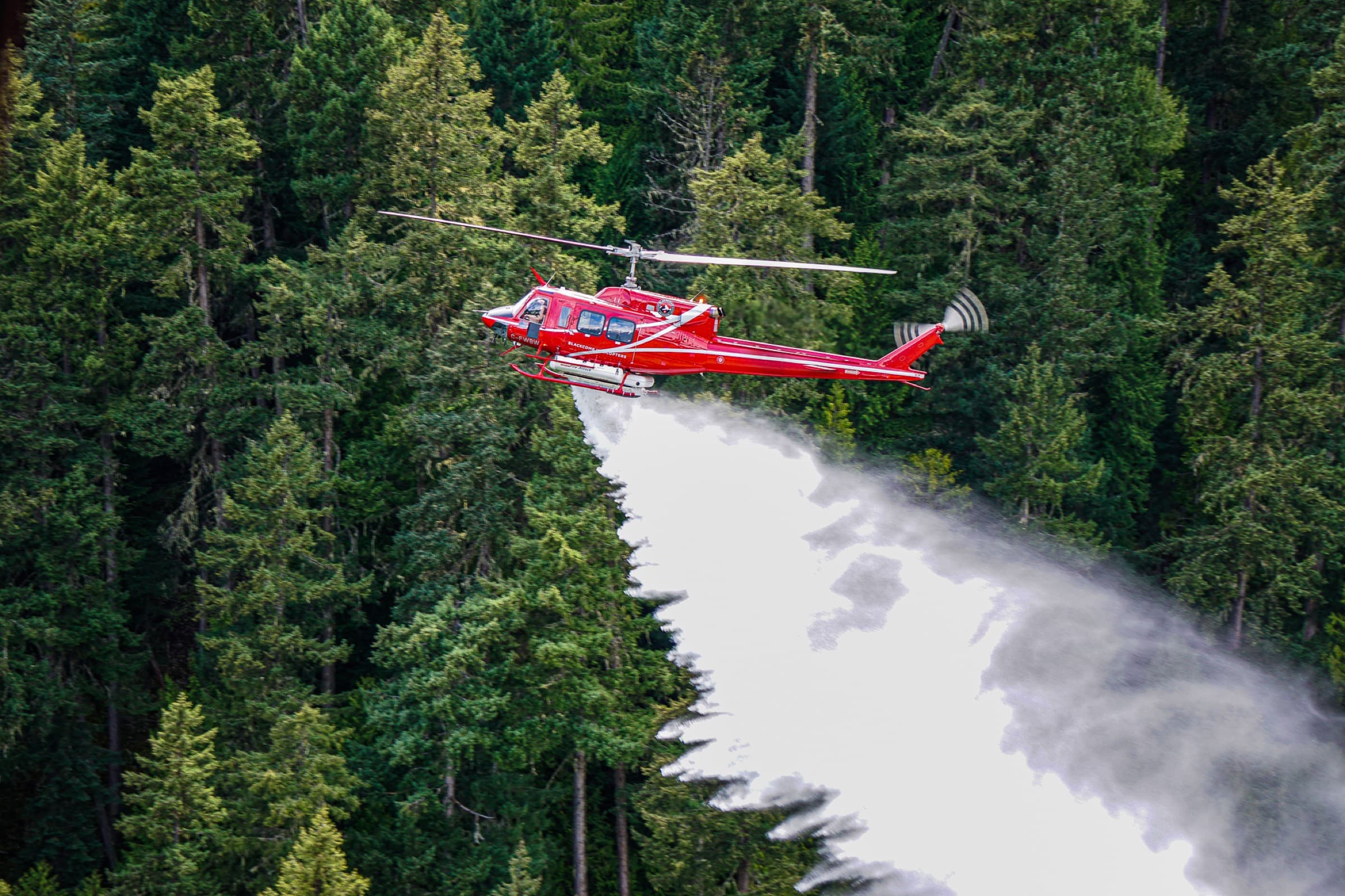 Bell helicopter water bombing in the Canadian Coast Mountains